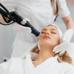 A Young Girl Gets A Charcoal Peeling For The Skin Of The Face In A Beauty Salon. Laser Pulses Cleanse The Skin. Hardware Cosmetology. The Process Of Photothermolysis, Warming The Skin