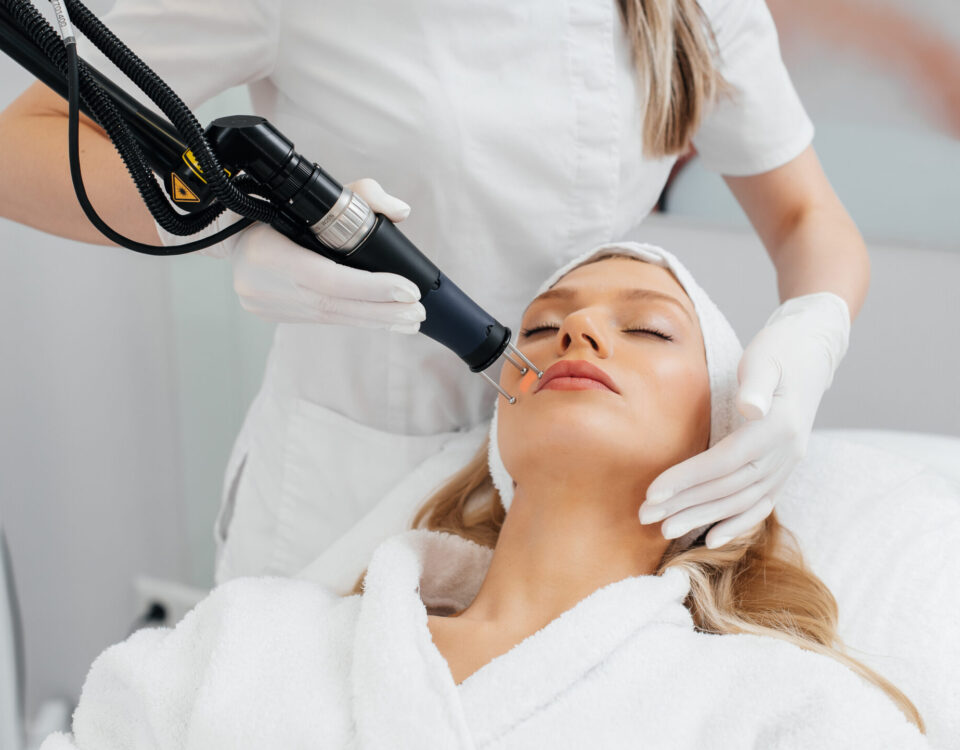 A Young Girl Gets A Charcoal Peeling For The Skin Of The Face In A Beauty Salon. Laser Pulses Cleanse The Skin. Hardware Cosmetology. The Process Of Photothermolysis, Warming The Skin